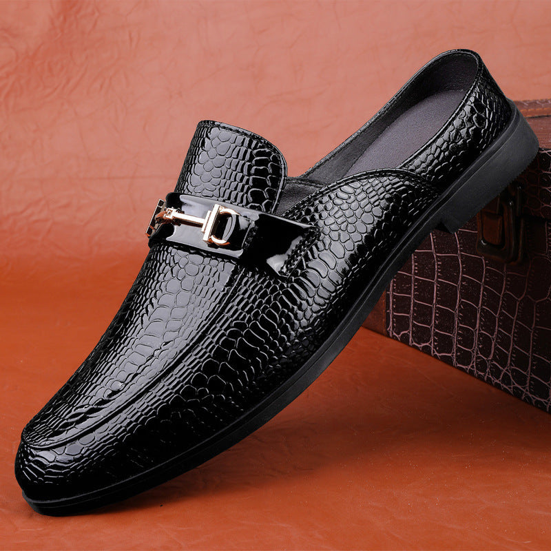 Scarpa mocassino uomo in pelle nera lucida con motivo coccodrillo, fibbia metallica decorativa, su sfondo marrone. Elegante calzatura formale.