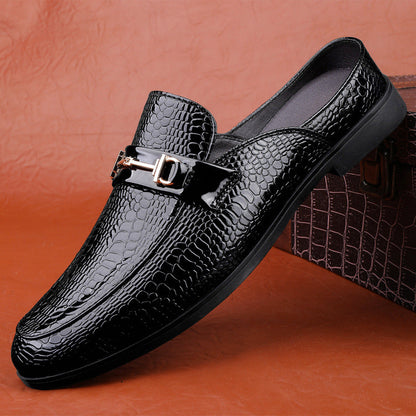 Scarpa mocassino uomo in pelle nera lucida con motivo coccodrillo, fibbia metallica decorativa, su sfondo marrone. Elegante calzatura formale.