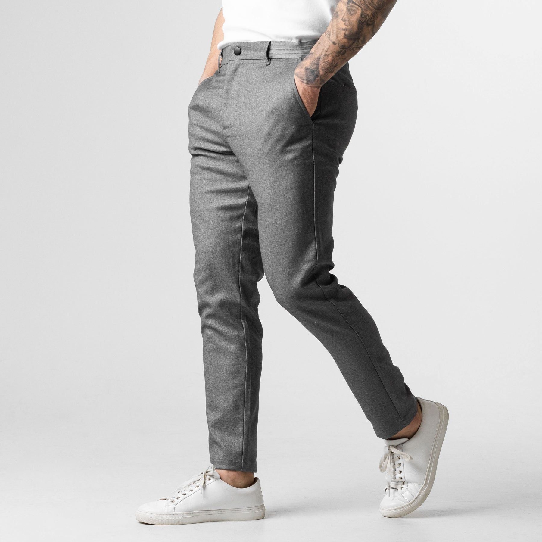 Pantaloni grigi eleganti da uomo, vestibilità slim, abbinati a scarpe da ginnastica bianche. Stile moderno e casual per un look versatile.