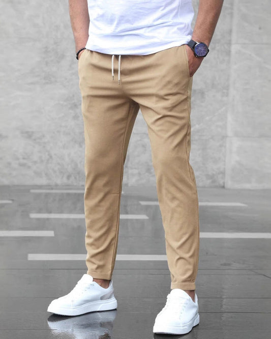Uomo in pantaloni chino beige e scarpe da ginnastica bianche, camicia bianca, orologio nero. Moda casual maschile, stile urbano elegante.