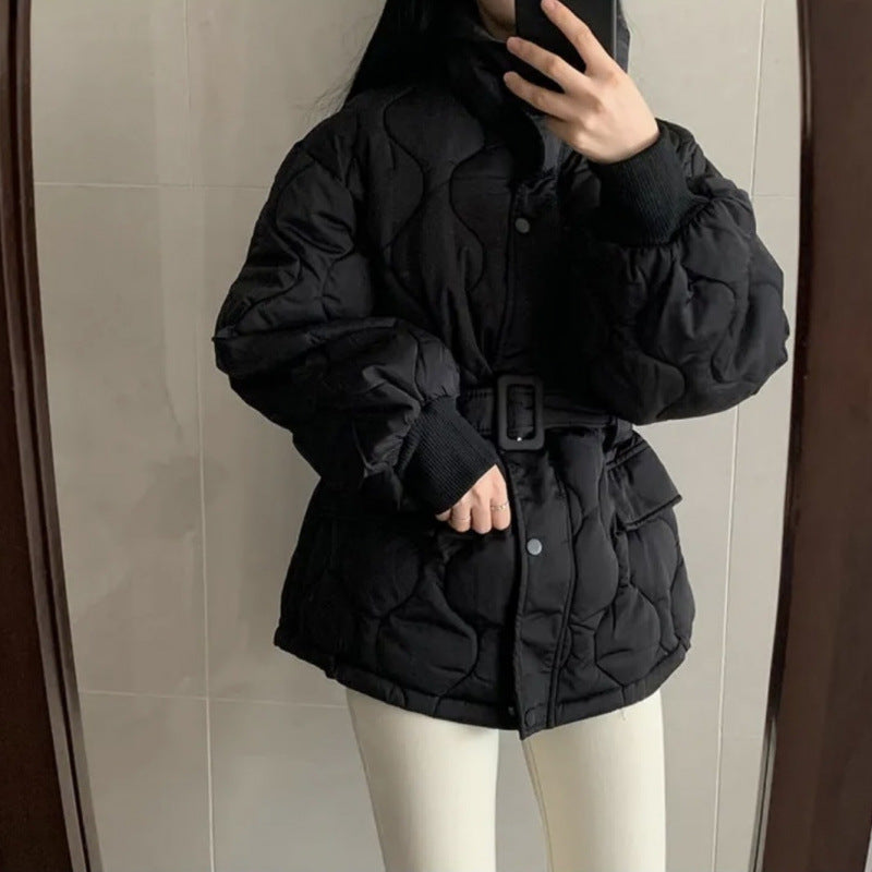 Donna in giacca nera imbottita con cintura, scatta selfie allo specchio. Moda invernale, abbigliamento caldo, stile casual.