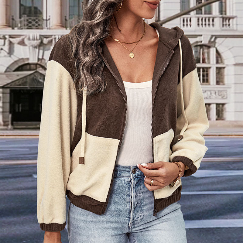 Donna con giacca a vento bicolore marrone e beige, top bianco e jeans, in città. Moda autunnale, abbigliamento casual, stile urbano.