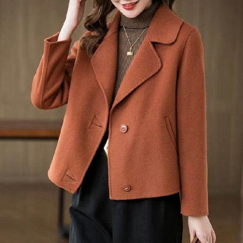 Donna con giacca marrone elegante, collo a revers, abbinata a maglione marrone e pantaloni neri. Moda autunnale, abbigliamento casual chic.