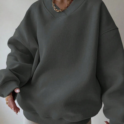 Donna con felpa oversize grigia, collana dorata, stile casual chic. Moda autunnale, abbigliamento comodo, tendenze streetwear.