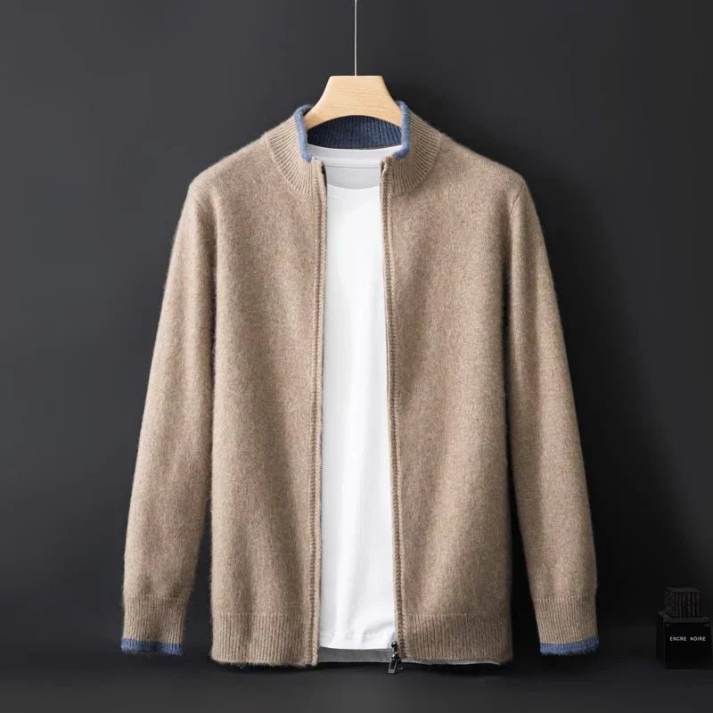 Cardigan beige in cashmere su gruccia, con zip frontale, colletto rialzato e dettagli blu ai polsini. Sfondo nero elegante.