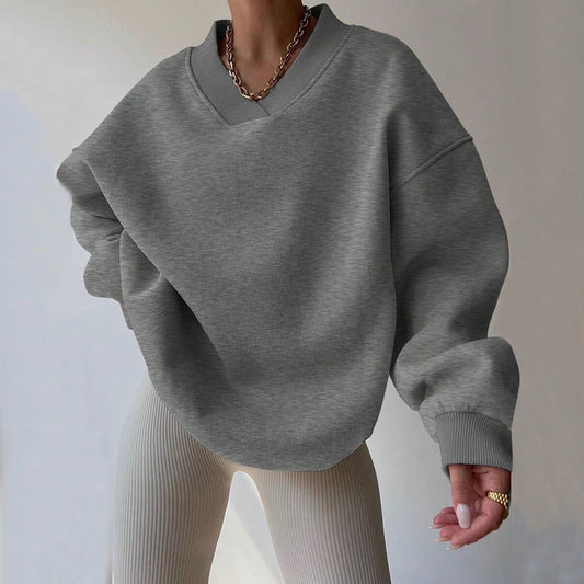 Donna indossa maglione oversize grigio e pantaloni a coste beige. Stile casual, moda autunnale, collana a catena dorata. Outfit trendy e confortevole.