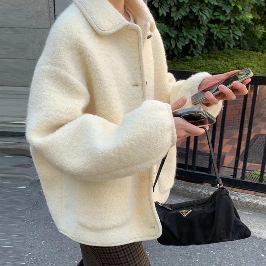 Giacca in lana bianca oversize, donna con smartphone e borsa Prada nera, moda autunnale, street style elegante, tendenze abbigliamento 2023.