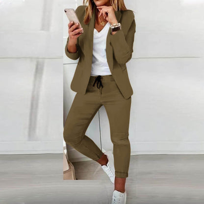 Donna in abito casual elegante, giacca e pantaloni color kaki, maglietta bianca, scarpe da ginnastica bianche, smartphone in mano. Moda femminile moderna.