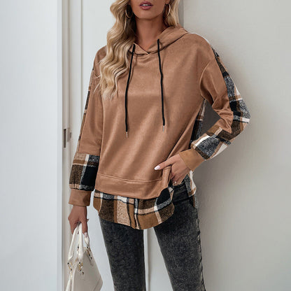 Donna con felpa marrone e dettagli a quadri, pantaloni grigi, borsa bianca. Moda casual autunnale, abbigliamento femminile trendy.