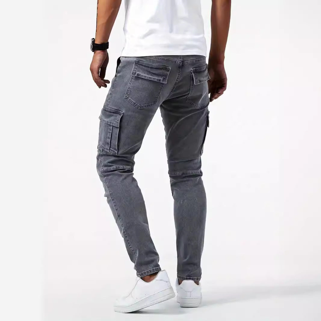 Uomo in jeans cargo grigi, tasche laterali, indossa scarpe bianche e maglietta bianca. Stile casual, moda maschile, abbigliamento urbano.
