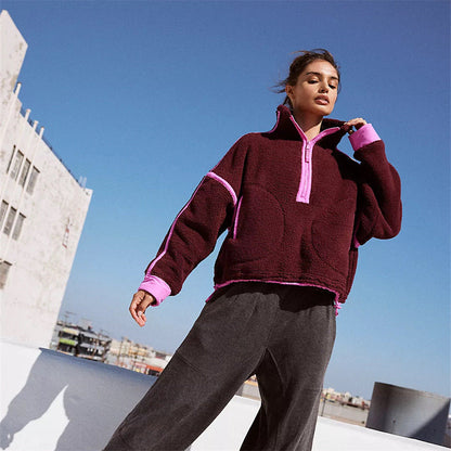 Donna con felpa oversize bordeaux e dettagli rosa su tetto urbano. Moda autunno, abbigliamento casual, stile streetwear.