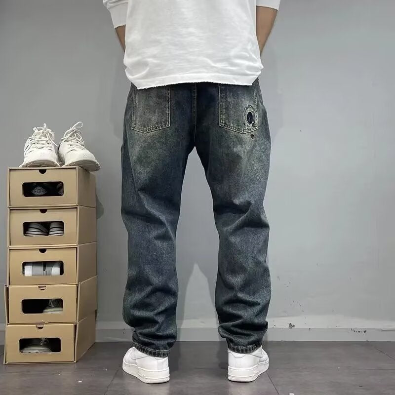 Uomo in jeans larghi e scarpe bianche, accanto a scatole di scarpe impilate. Moda casual, abbigliamento streetwear, tendenze denim.