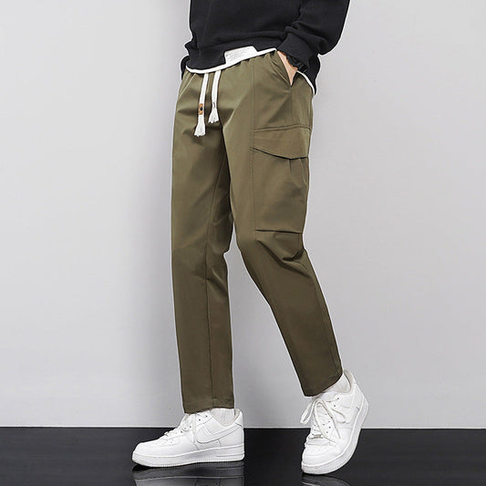 Pantaloni cargo uomo verde oliva, tasche laterali, cordoncino in vita, abbinati a sneakers bianche. Stile casual e moderno.