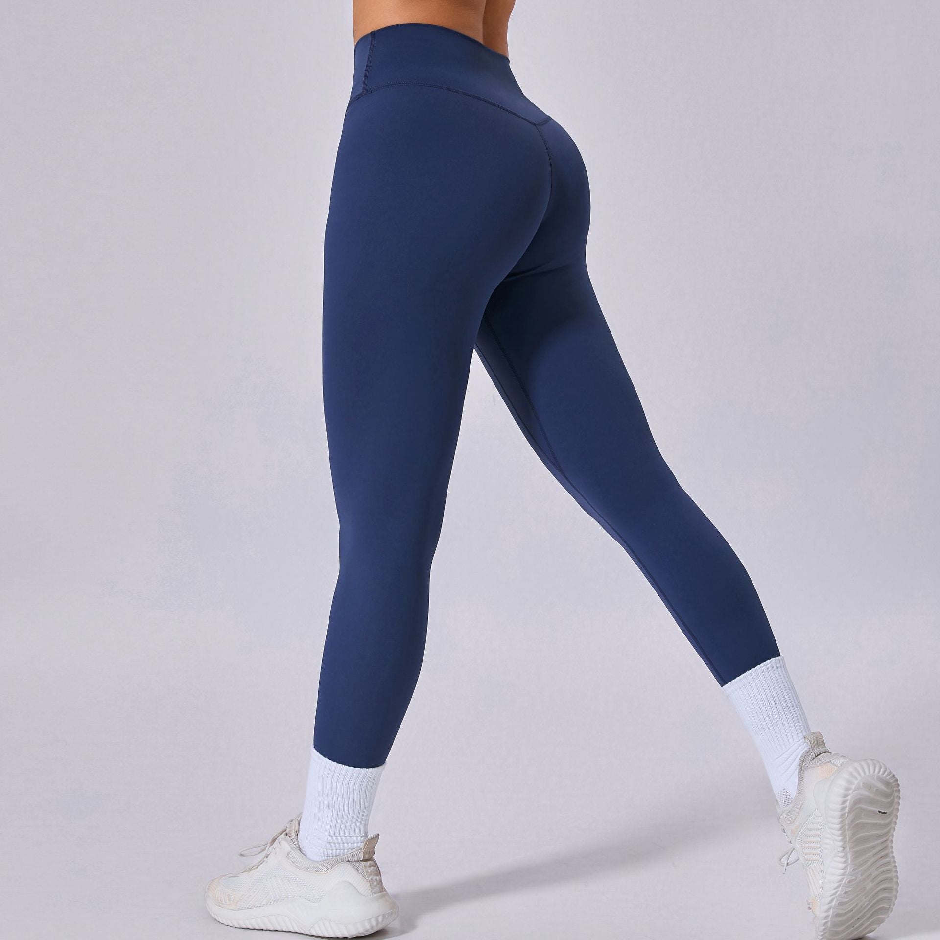 Leggings sportivi blu scuro, indossati con scarpe da ginnastica bianche e calzini alti. Abbigliamento fitness donna, moda activewear.