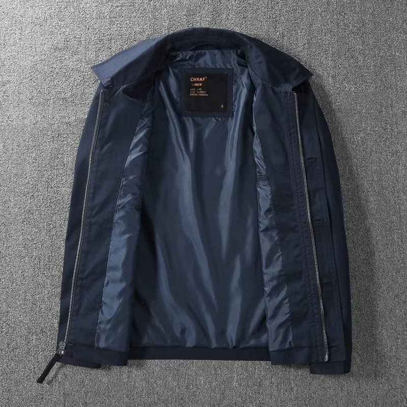 Giacca blu scuro da uomo aperta, con fodera interna in tessuto lucido, zip laterali, su sfondo grigio. Elegante e moderna, ideale per l'autunno.
