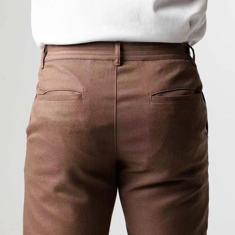 Pantaloni marroni eleganti da uomo, vista posteriore, indossati con camicia bianca. Tessuto di alta qualità, stile formale, moda maschile.