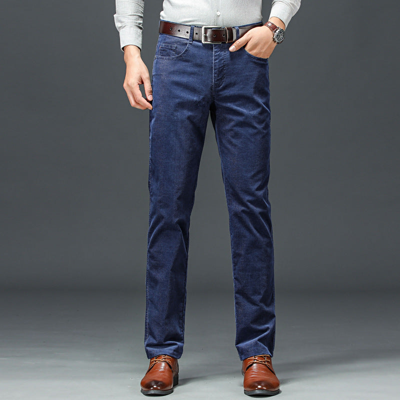 Uomo in jeans blu scuro, camicia grigia e scarpe marroni eleganti, sfondo grigio. Moda maschile casual, abbigliamento autunnale.