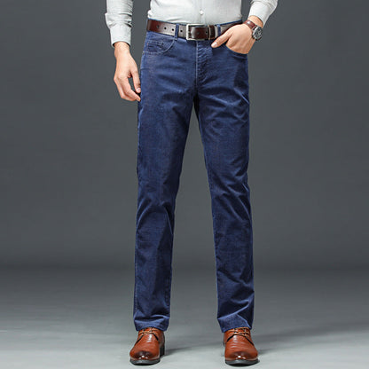 Uomo in jeans blu scuro, camicia grigia e scarpe marroni eleganti, sfondo grigio. Moda maschile casual, abbigliamento autunnale.