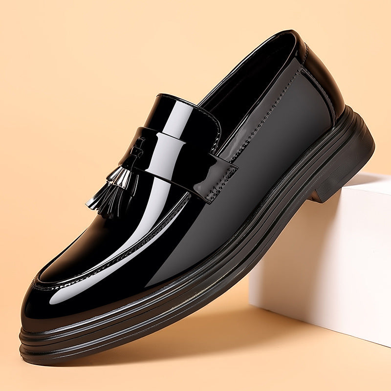 Scarpa mocassino uomo in pelle nera lucida con nappine, su sfondo beige. Elegante calzatura formale, moda maschile, stile classico.
