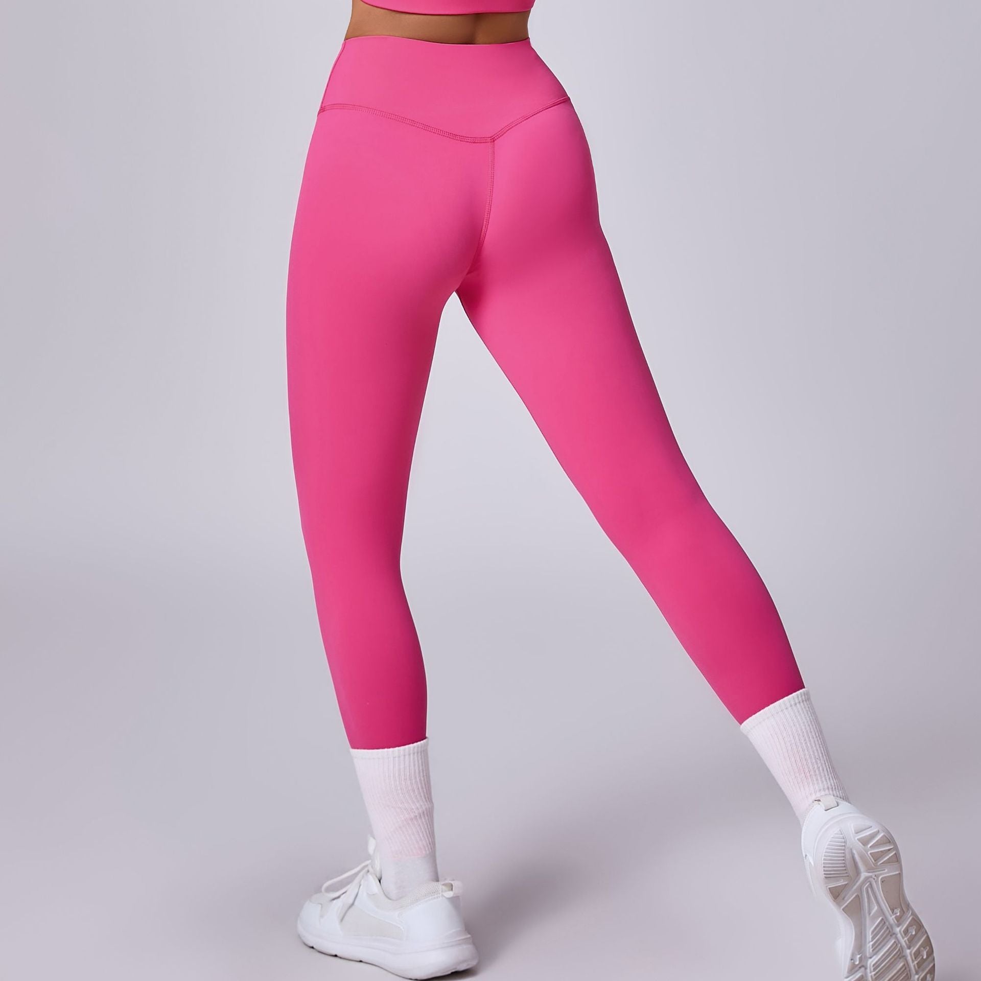 Leggings sportivi rosa acceso, indossati con scarpe da ginnastica bianche e calzini alti. Abbigliamento fitness donna, moda activewear.