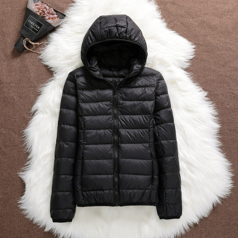 Giacca invernale nera con cappuccio su sfondo bianco peloso, moda abbigliamento caldo, piumino leggero, stile casual, tendenza autunno inverno.