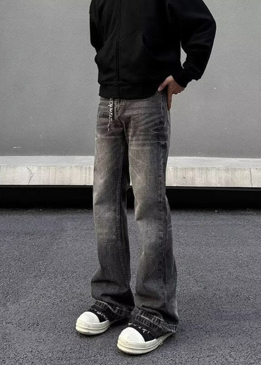 Jeans larghi grigi vintage, scarpe da ginnastica bianche e nere, felpa nera; moda streetwear casual, tendenze abbigliamento urbano.