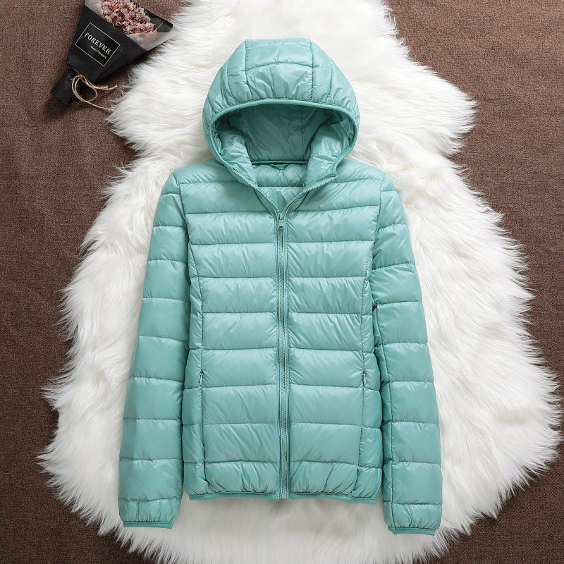 Giacca invernale verde menta con cappuccio, imbottita e trapuntata, su sfondo di pelliccia bianca. Moda donna, abbigliamento caldo e trendy.