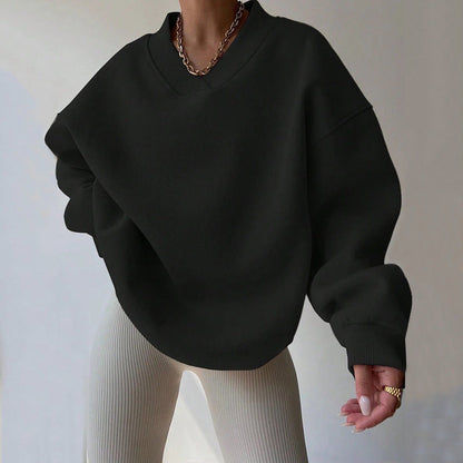 Donna con maglione oversize nero e pantaloni a coste beige. Moda casual, stile autunnale, abbigliamento femminile trendy.