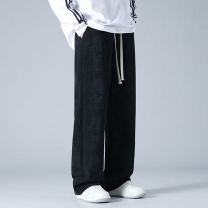 Pantaloni neri larghi da uomo, stile casual, con coulisse, abbinati a scarpe bianche e maglia bianca. Moda streetwear maschile.