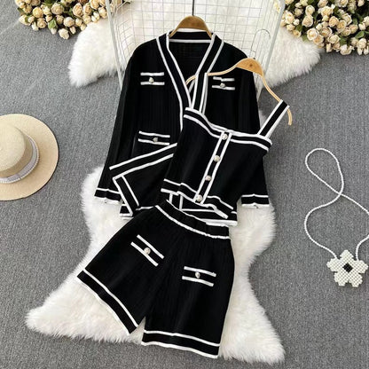 Completo estivo donna nero con dettagli bianchi, composto da giacca, top e pantaloncini. Elegante abbigliamento moda su sfondo grigio con accessori.