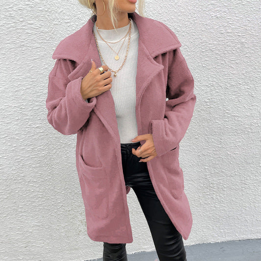 Donna con cappotto rosa in lana, maglia bianca e pantaloni neri in pelle. Moda autunnale, stile casual chic, accessori con collane dorate.