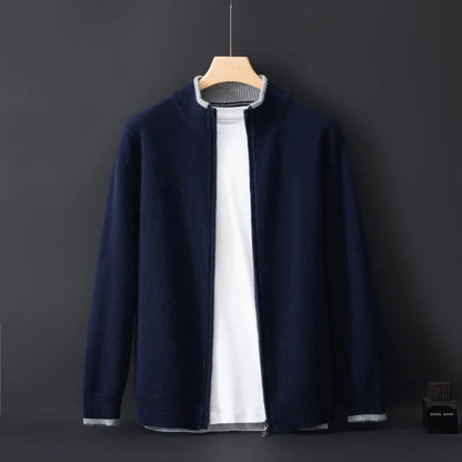Cardigan blu scuro da uomo su sfondo nero, appeso a una gruccia, con zip aperta e maglietta bianca sotto. Moda maschile elegante e casual.