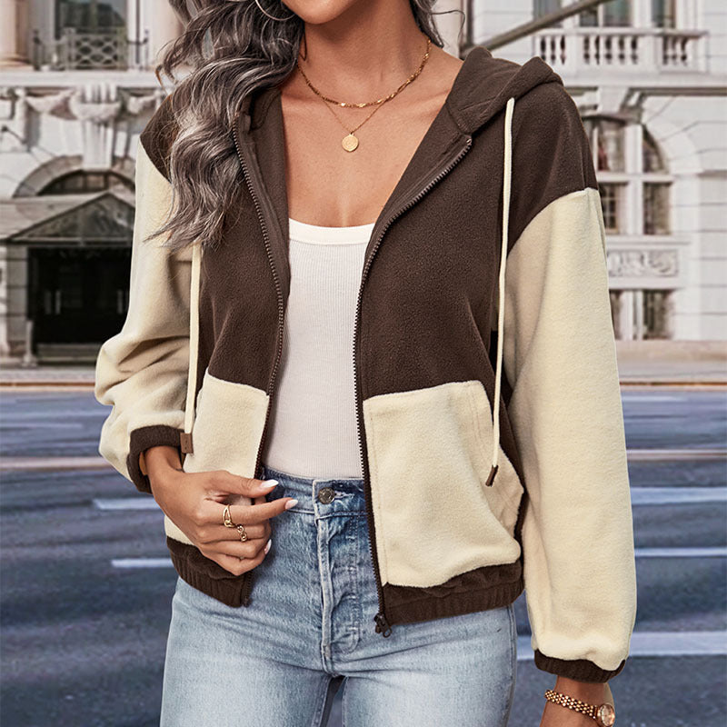 Donna con giacca a vento bicolore marrone e beige, top bianco e jeans, in città. Moda autunnale, abbigliamento casual, stile urbano.