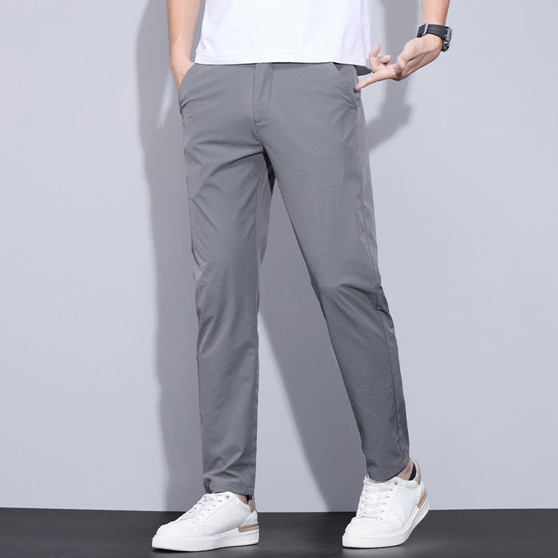 Pantaloni chino grigi da uomo, abbinati a scarpe da ginnastica bianche e t-shirt bianca. Stile casual elegante, moda maschile moderna.