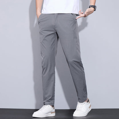 Pantaloni chino grigi da uomo, abbinati a scarpe da ginnastica bianche e t-shirt bianca. Stile casual elegante, moda maschile moderna.