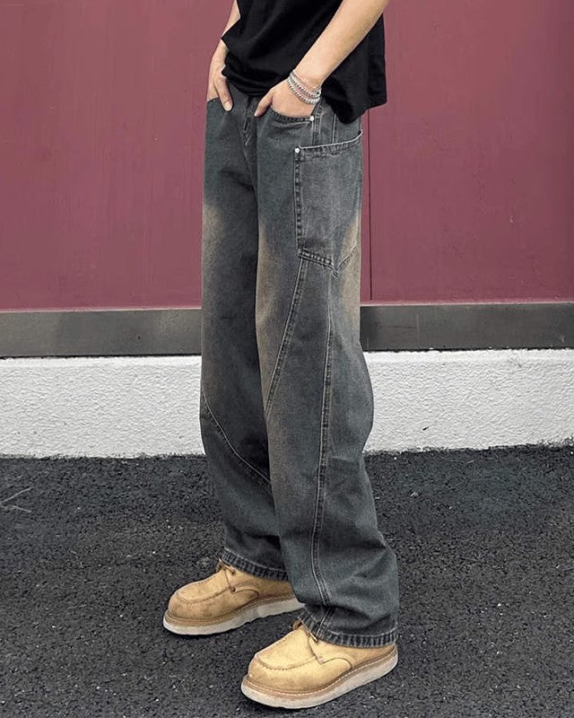 Jeans larghi vintage grigi, indossati con scarpe beige su sfondo rosa. Moda casual uomo, stile streetwear, pantaloni oversize.