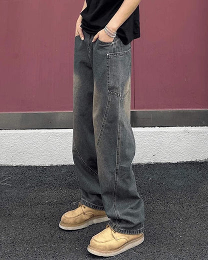 Jeans larghi vintage grigi, indossati con scarpe beige su sfondo rosa. Moda casual uomo, stile streetwear, pantaloni oversize.