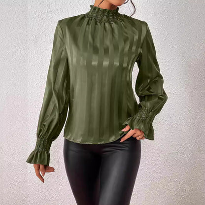 Blusa verde oliva a righe verticali con maniche lunghe e polsini arricciati, abbinata a pantaloni in pelle nera. Moda elegante e sofisticata.