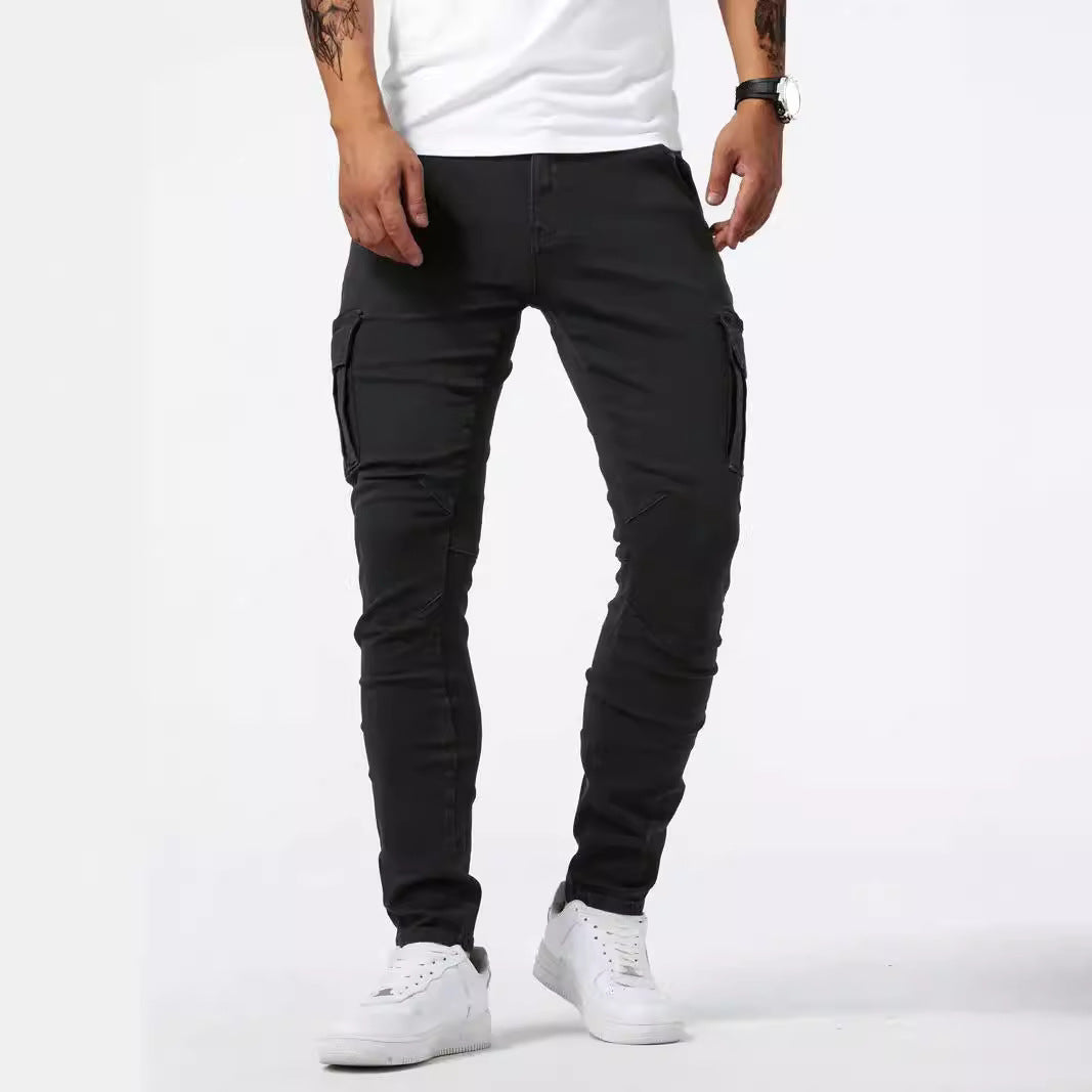 Jeans cargo neri da uomo, vestibilità slim, con tasche laterali, abbinati a scarpe da ginnastica bianche e maglietta bianca.