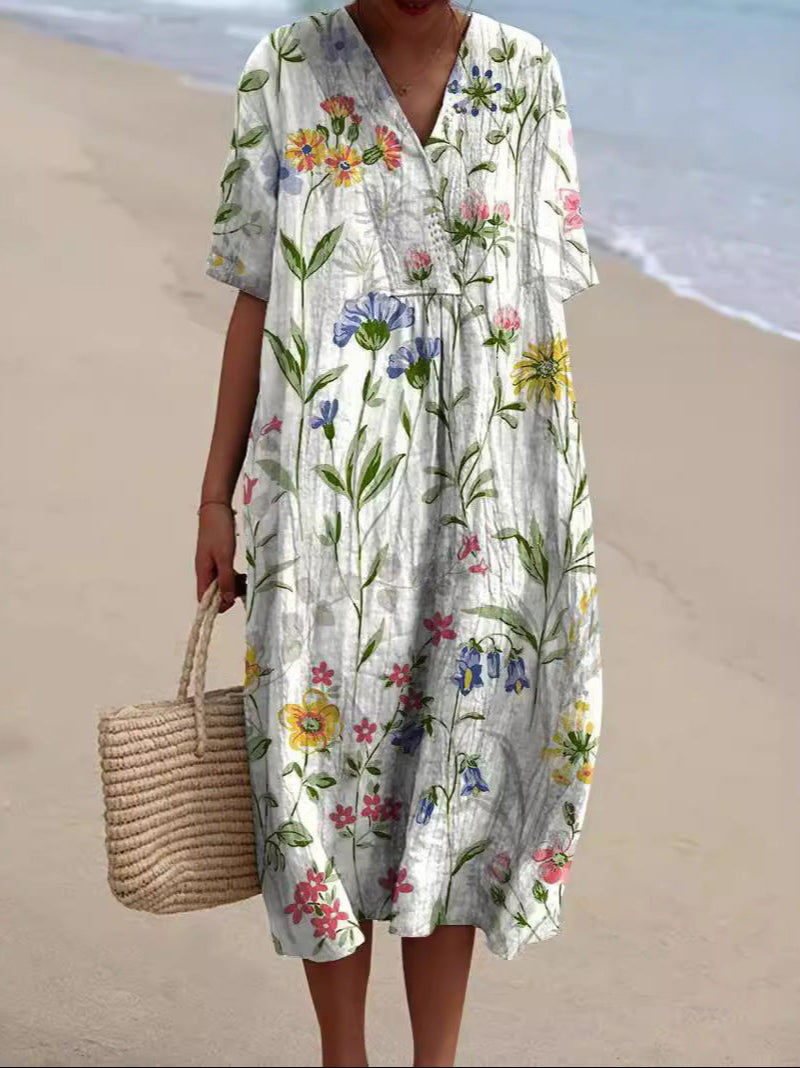 Donna in abito estivo floreale lungo sulla spiaggia, con borsa di paglia. Moda mare, abbigliamento estivo, stile casual elegante.