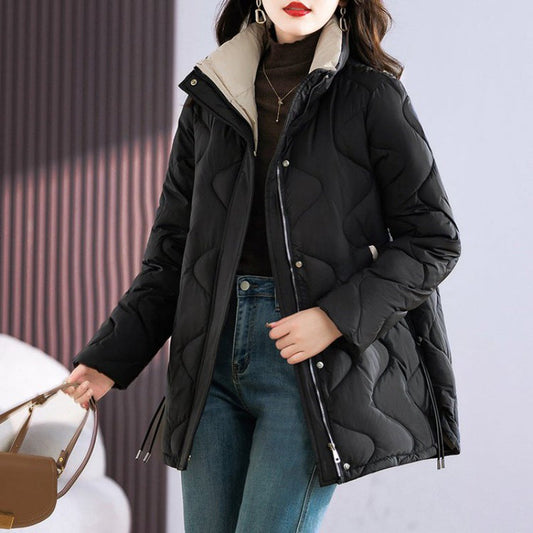 Donna con giacca invernale nera imbottita, zip frontale, collo alto, indossa jeans blu e maglione marrone. Moda autunnale, abbigliamento caldo.