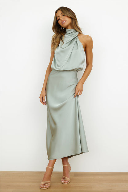 Donna in abito lungo verde salvia elegante, senza maniche, con scollo drappeggiato. Indossa sandali con tacco. Moda femminile, abbigliamento elegante.