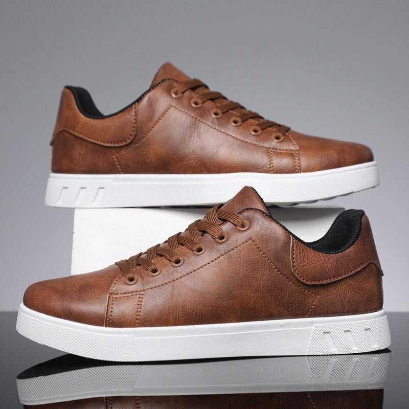 Scarpe da ginnastica marroni in pelle sintetica con suola bianca, design moderno, lacci marroni, su sfondo grigio. Scarpe casual eleganti uomo.