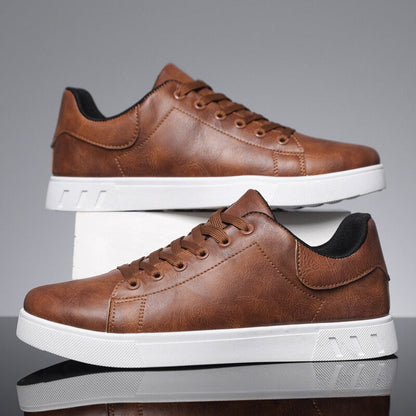 Scarpe da ginnastica marroni in pelle sintetica con suola bianca, design moderno, lacci marroni, su sfondo grigio. Scarpe casual eleganti uomo.