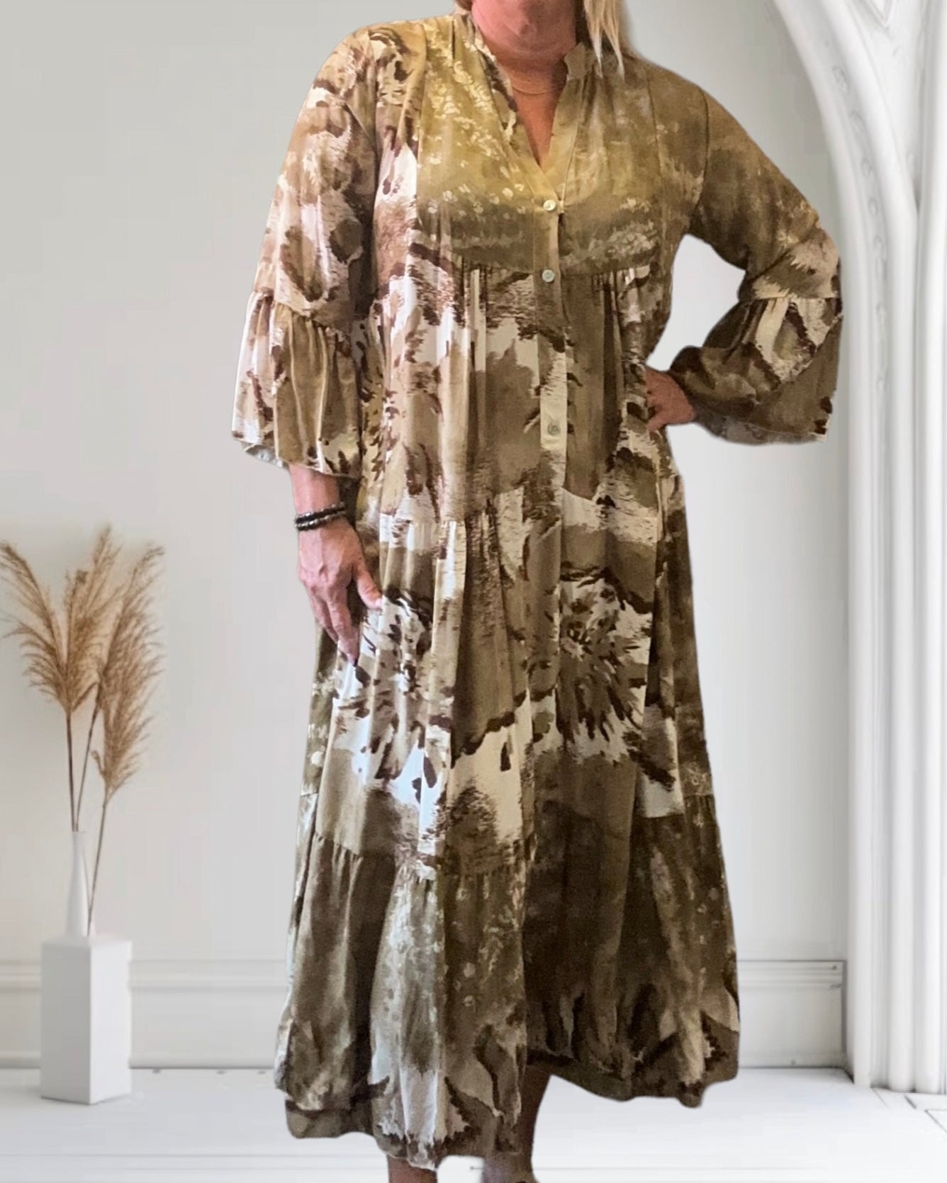 Abito lungo donna in tessuto floreale marrone, maniche lunghe, sfondo bianco con decorazioni minimaliste. Moda femminile elegante e casual.