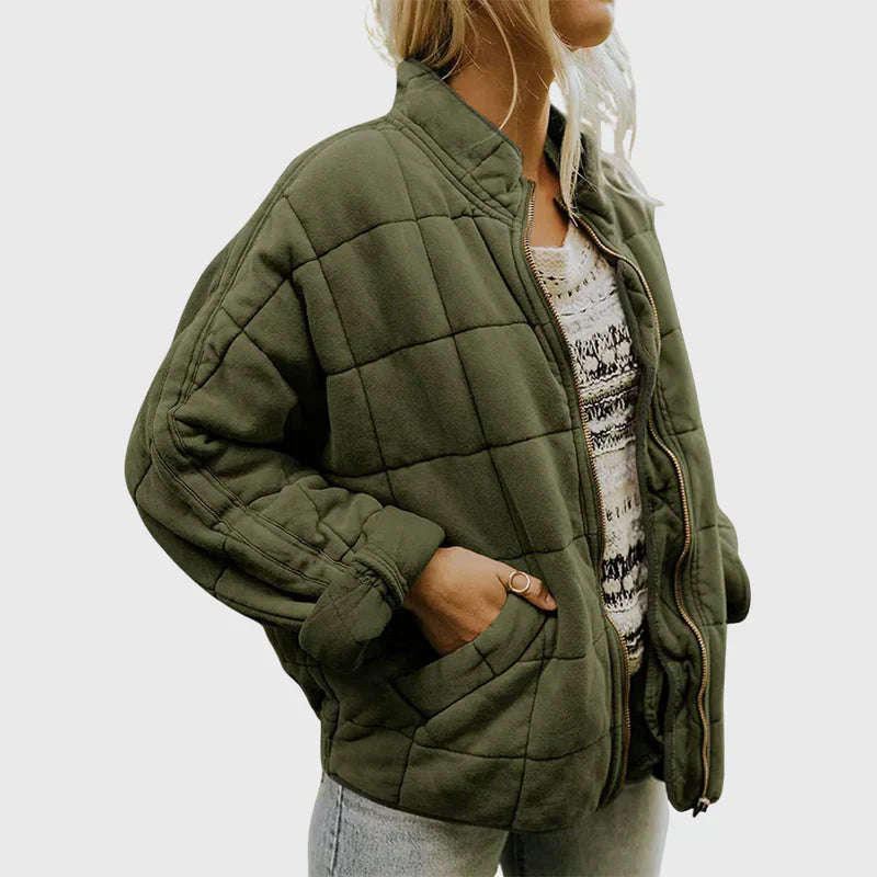 Giacca trapuntata verde oliva da donna, stile casual, con zip frontale e tasche, indossata su maglia bianca a motivi, moda autunnale.