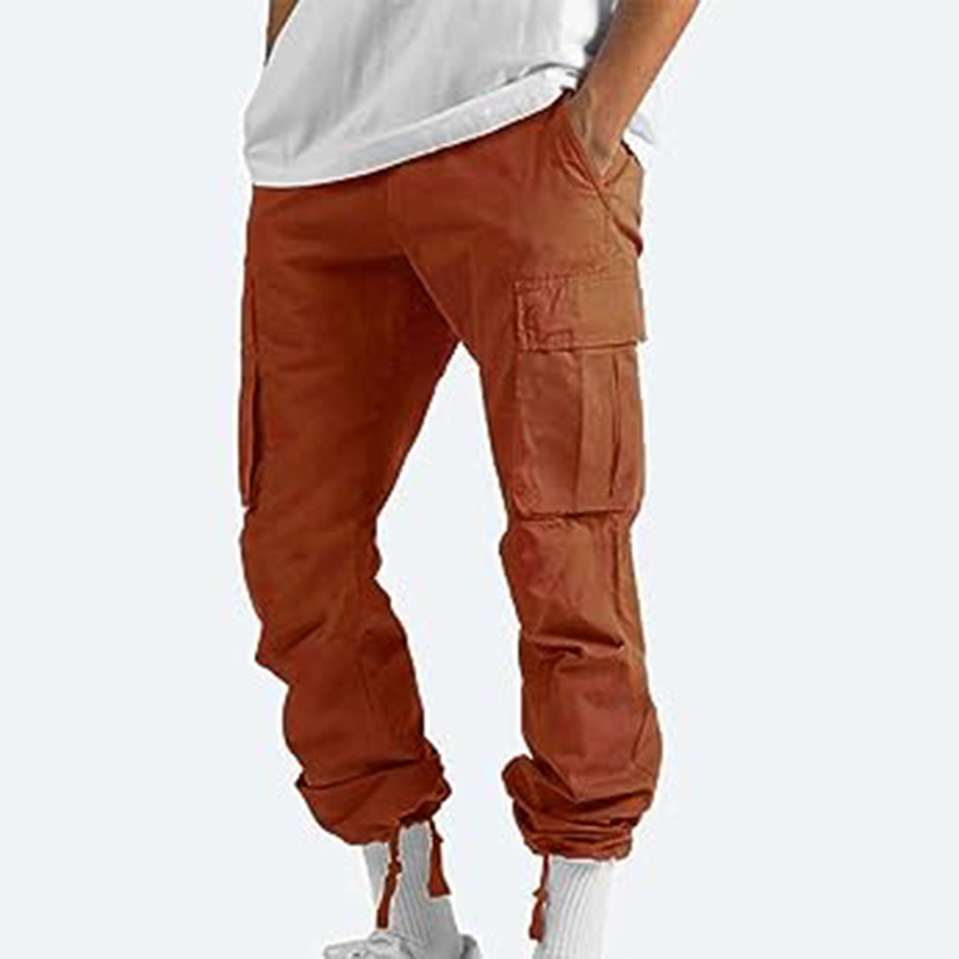 Pantaloni cargo uomo arancioni, tasche multiple, stile casual, abbinati a maglietta bianca e calze bianche, moda streetwear contemporanea.