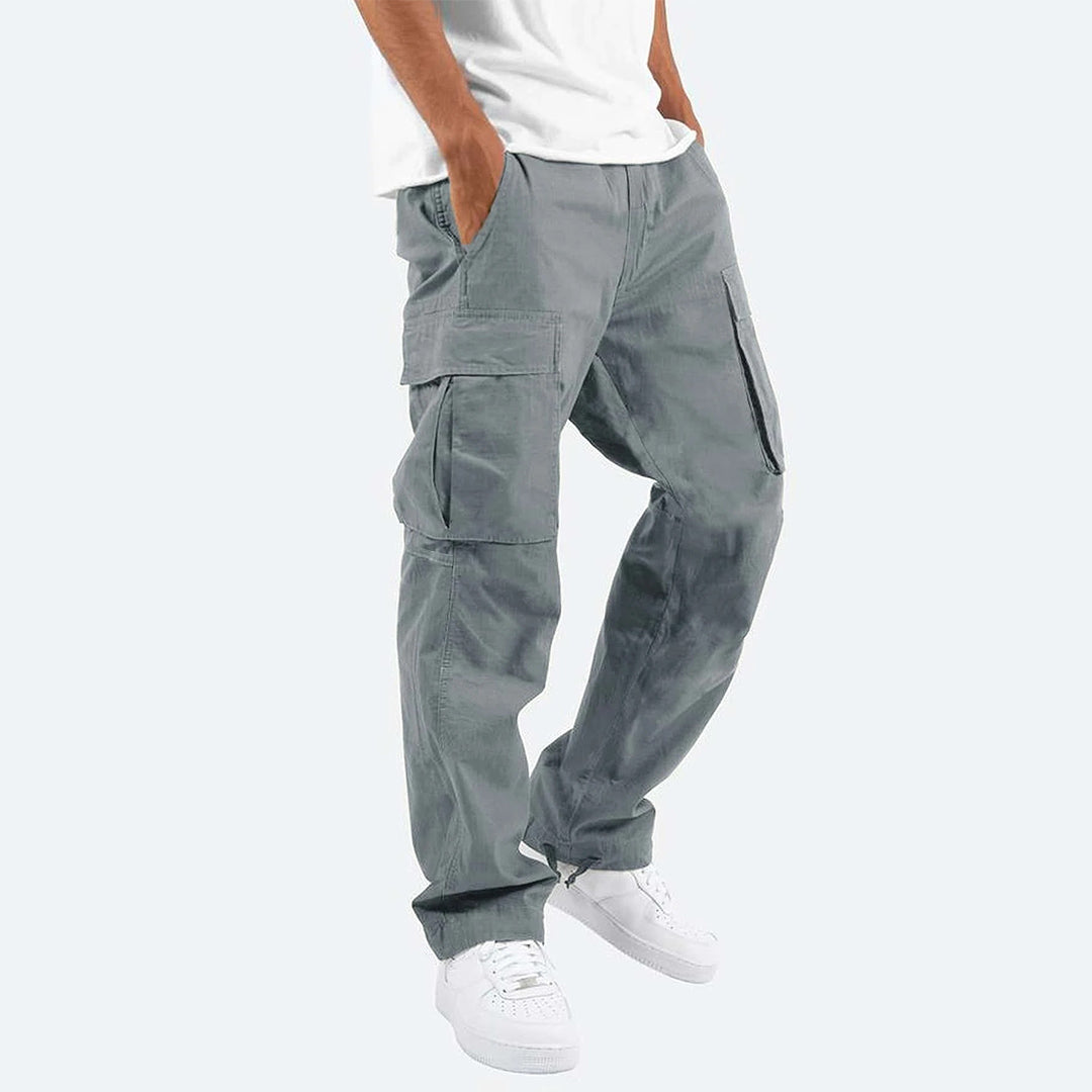 Pantaloni cargo grigi da uomo, tasche multiple, stile casual, abbinati a scarpe bianche e maglietta bianca. Moda urbana maschile.