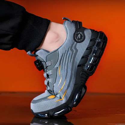 Scarpa sportiva grigia con suola ammortizzata nera, design moderno e dettagli arancioni, su sfondo arancione. Calzatura da corsa, moda sportiva.