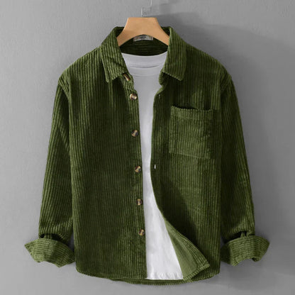 Camicia di velluto a coste verde oliva su gruccia, con tasca frontale e bottoni in legno, sopra una maglietta bianca. Moda uomo casual elegante.